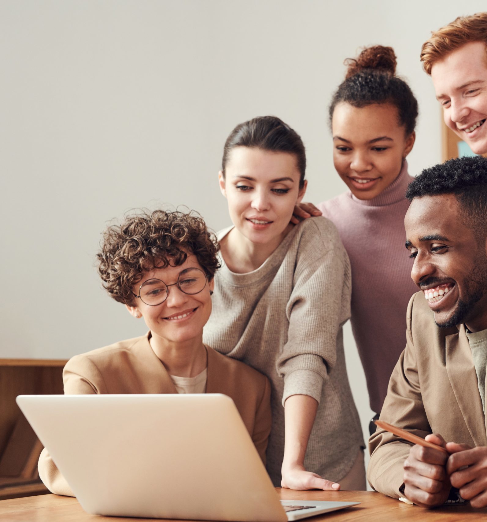 Group of people gathered around a laptop, smiling and discussing a project